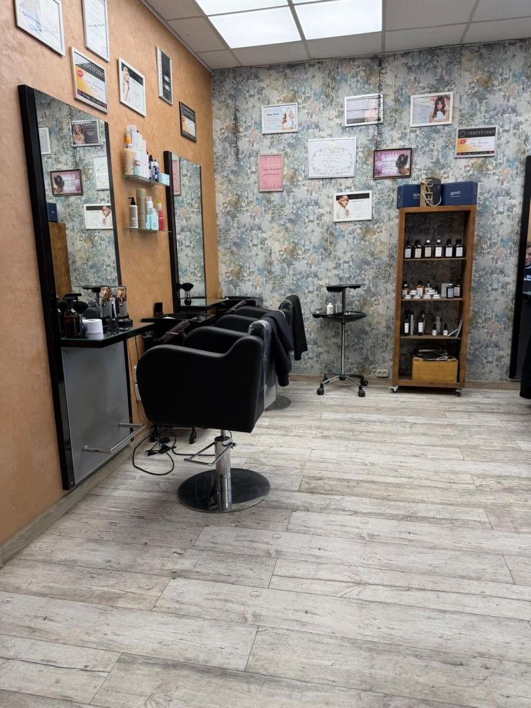 Sala fryzjerska — fotele, lustra i ściana z certyfikatami